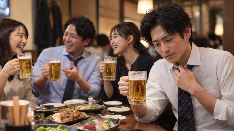 平日の飲み会でビールを片手に談笑する会社員たち